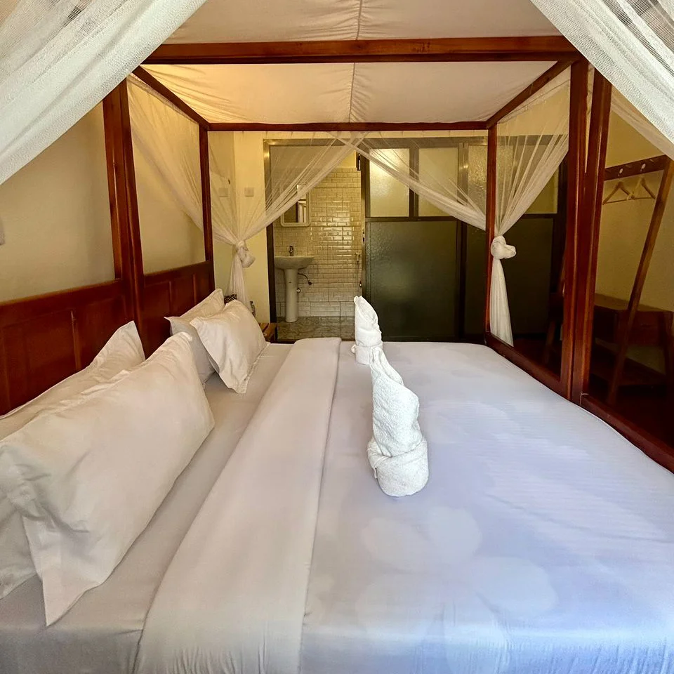 Single suite room with a four-poster bed and mosquito net.